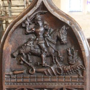 A medieval carved bench end showing a mounted figure